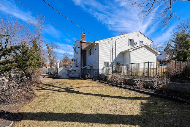 rear view of property with a wooden deck, a chimney, a yard, and fence