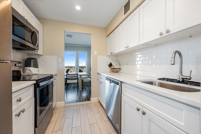 kitchen with light wood-style floors, white cabinetry, appliances with stainless steel finishes, and a sink