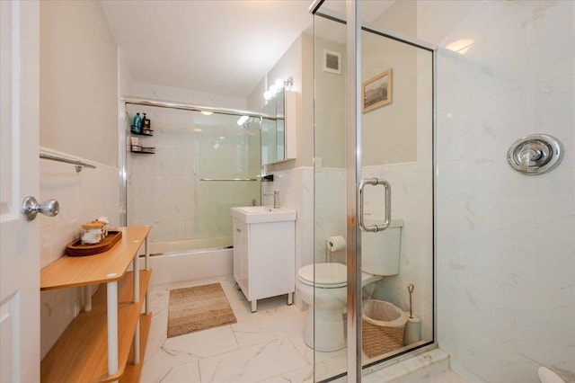 bathroom with toilet, marble finish floor, tile walls, and vanity