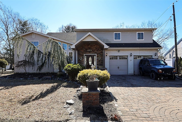 view of front facade featuring decorative driveway, stone siding, and an attached garage