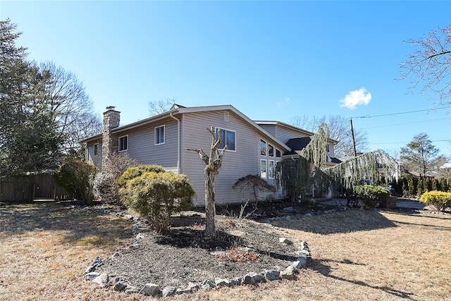 view of side of property with a chimney and fence