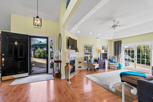 foyer with recessed lighting, ceiling fan with notable chandelier, a fireplace, baseboards, and wood-type flooring