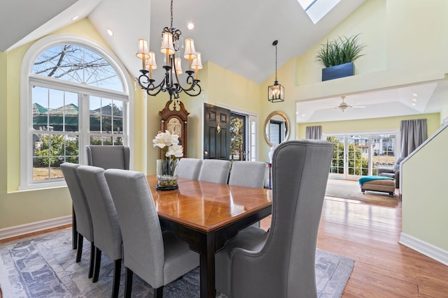 dining space featuring high vaulted ceiling, a notable chandelier, baseboards, and wood finished floors