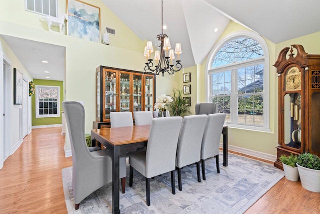 dining room with a chandelier, baseboards, visible vents, and light wood-style floors