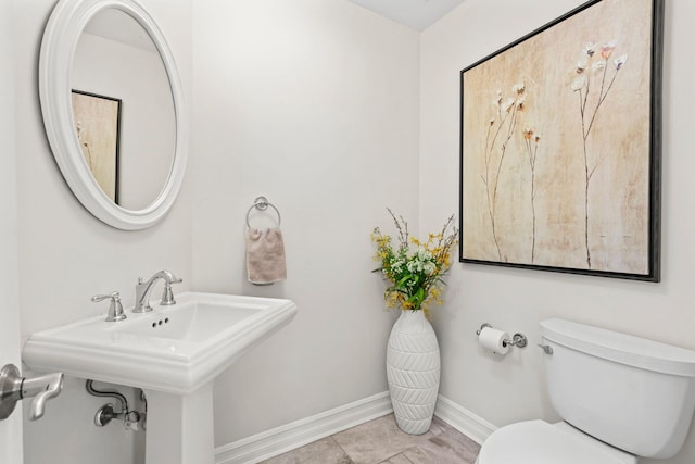 half bath featuring a sink, toilet, and baseboards