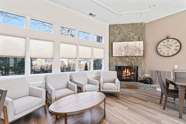 living room featuring ornamental molding, visible vents, a fireplace, and light wood-style flooring