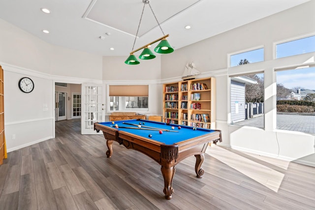 recreation room with french doors, wood finished floors, and a towering ceiling