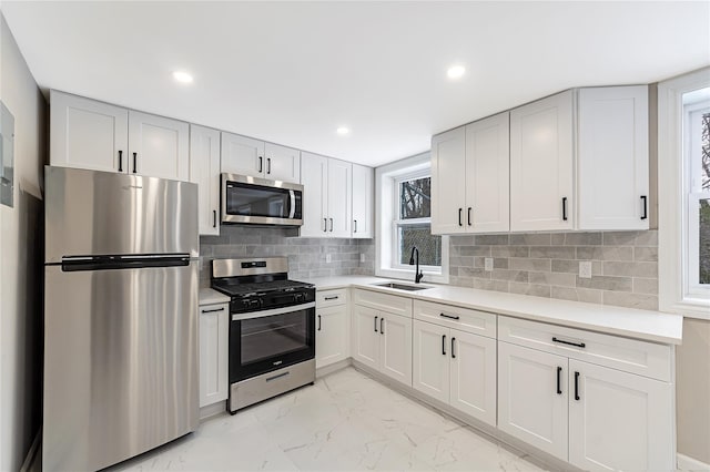 kitchen with stainless steel appliances, a sink, white cabinetry, light countertops, and marble finish floor