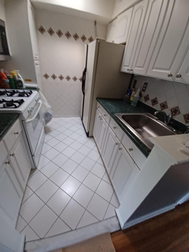 kitchen with refrigerator with ice dispenser, sink, white range with gas stovetop, white cabinets, and light tile patterned flooring