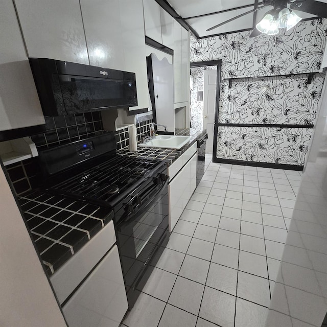 kitchen with light tile patterned flooring, a sink, white cabinetry, black appliances, and dark countertops