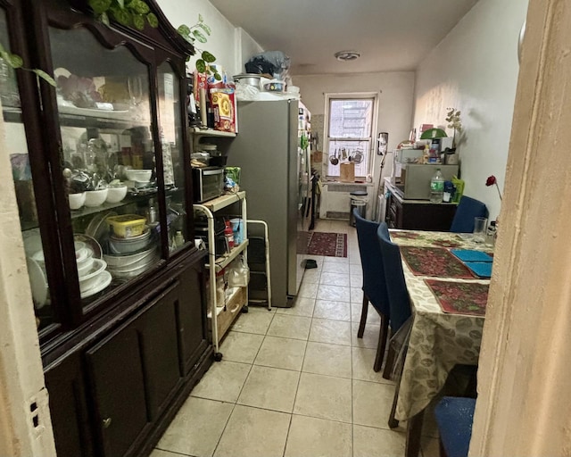 kitchen with stainless steel fridge, light tile patterned flooring, and dark brown cabinetry