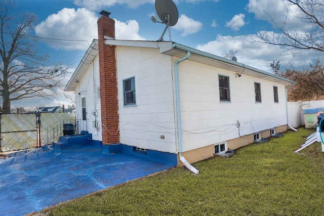 view of property exterior featuring a chimney, fence, and a yard