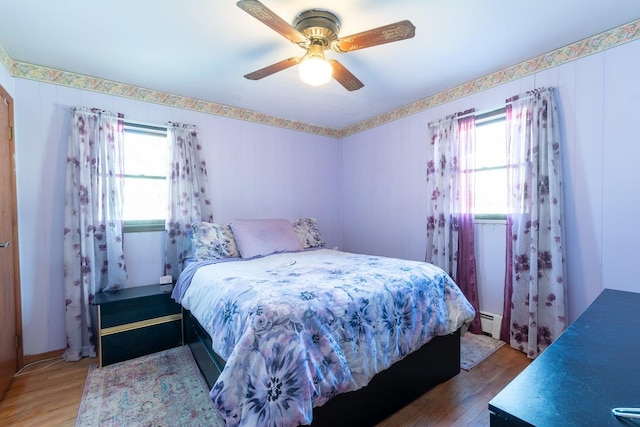 203 Front Ave, Brentwood, NY 11717 - bedroom featuring multiple windows, baseboard heating, wood finished floors, and a ceiling fan