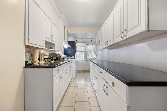 kitchen with dark countertops, light tile patterned floors, white cabinets, and white range with electric cooktop