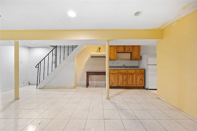 kitchen with light tile patterned floors, recessed lighting, brown cabinetry, freestanding refrigerator, and a sink