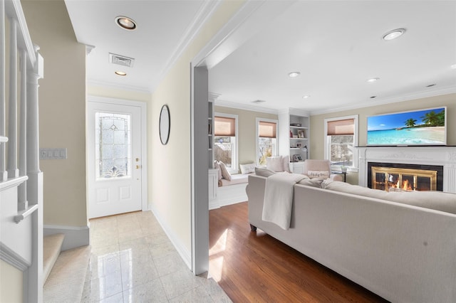 foyer with ornamental molding, a glass covered fireplace, visible vents, and recessed lighting