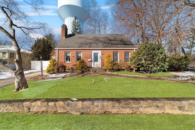 view of front of property with brick siding, fence, a chimney, and a front lawn