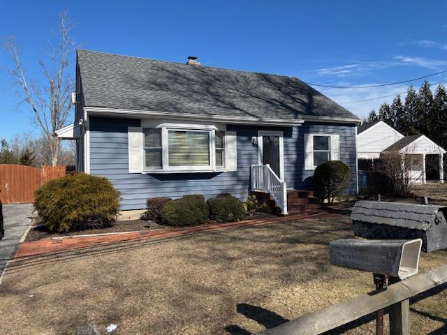 view of front of property featuring roof with shingles, a front yard, and fence