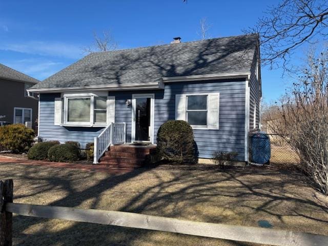 bungalow-style house featuring roof with shingles and fence