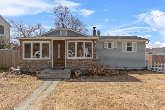 view of front facade with crawl space, stone siding, and fence