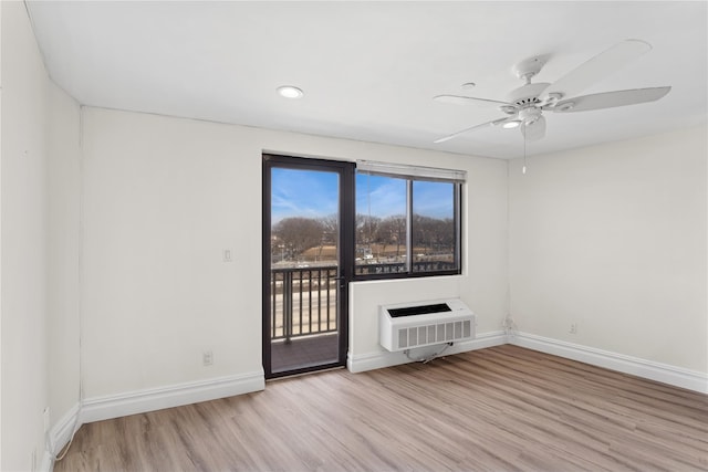 spare room featuring baseboards, an AC wall unit, wood finished floors, and a ceiling fan