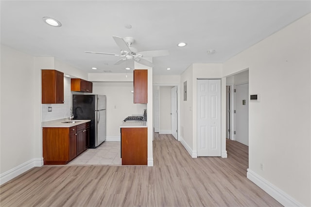 kitchen with recessed lighting, light countertops, freestanding refrigerator, and baseboards