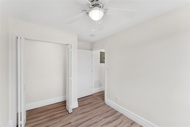unfurnished bedroom with electric panel, baseboards, a closet, and wood finished floors
