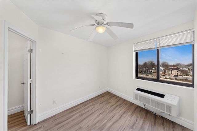 empty room with ceiling fan, baseboards, a wall mounted air conditioner, and wood finished floors