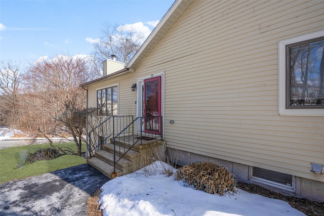 snow covered property entrance featuring a chimney