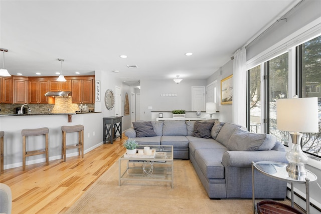 living area with light wood finished floors, baseboards, visible vents, a baseboard heating unit, and recessed lighting