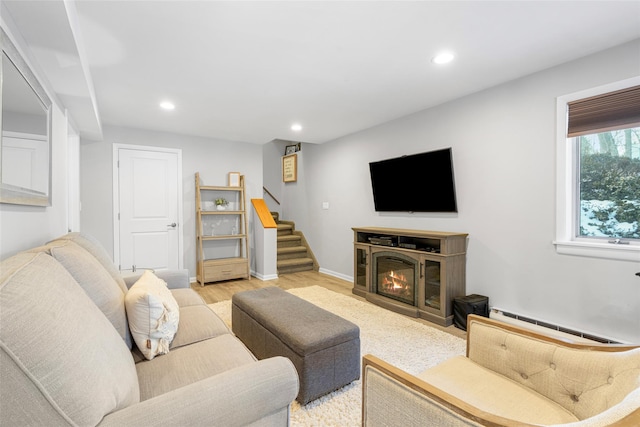 living area featuring stairs, light wood finished floors, a baseboard radiator, and recessed lighting