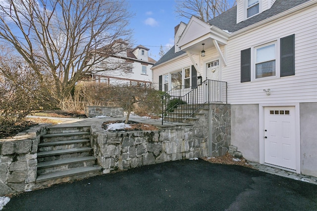 view of exterior entry featuring a shingled roof