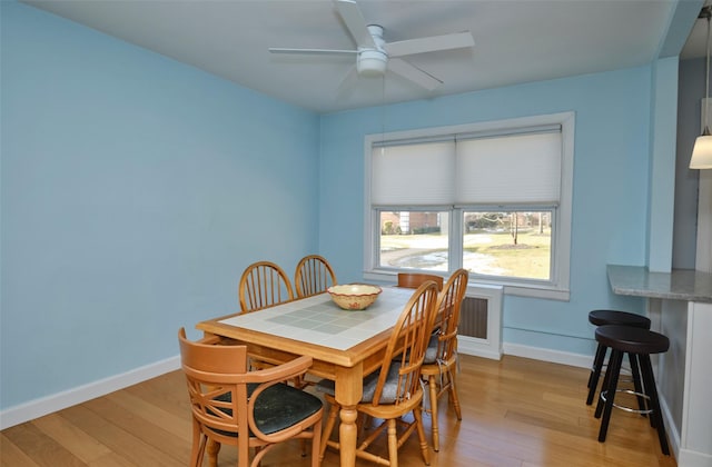 dining area featuring baseboards, a ceiling fan, and light wood-style flooring