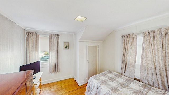 bedroom featuring ornamental molding, lofted ceiling, and light hardwood / wood-style flooring