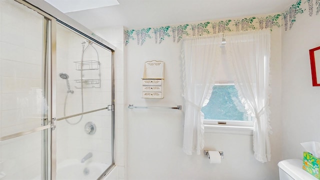 bathroom featuring combined bath / shower with glass door and toilet