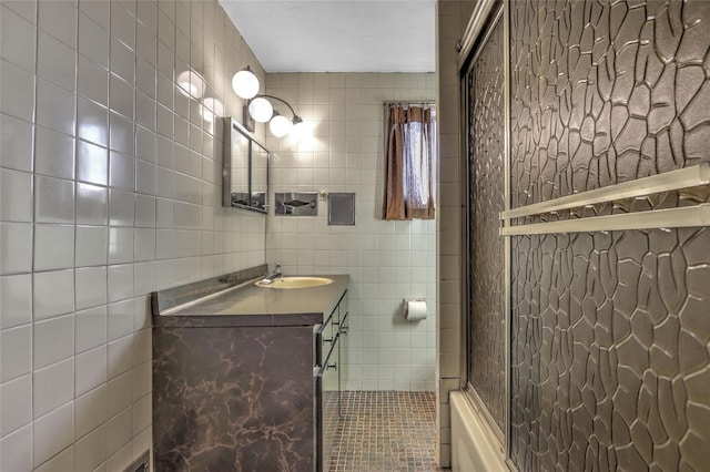 full bathroom featuring combined bath / shower with glass door, tile walls, and vanity