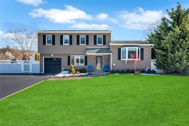 view of front of property featuring a front yard, driveway, an attached garage, and fence