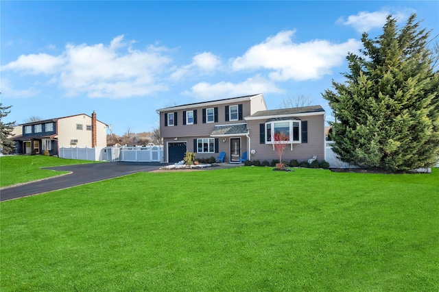 view of front of property featuring a garage, fence, a front lawn, and aphalt driveway