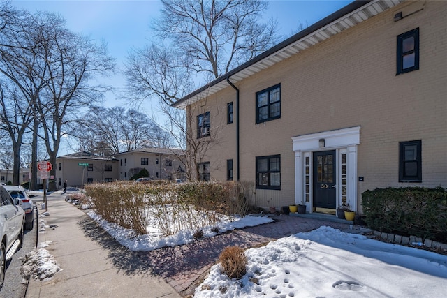 view of snowy exterior with brick siding