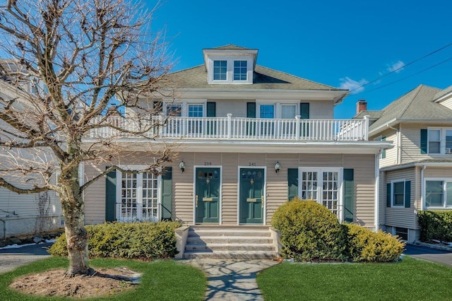 american foursquare style home featuring entry steps and a balcony