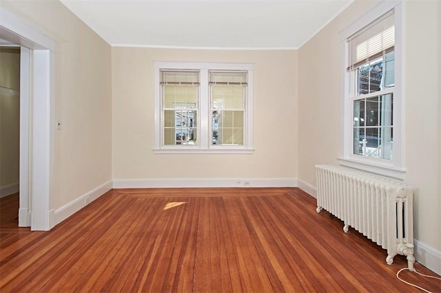 empty room with radiator heating unit, wood finished floors, and baseboards