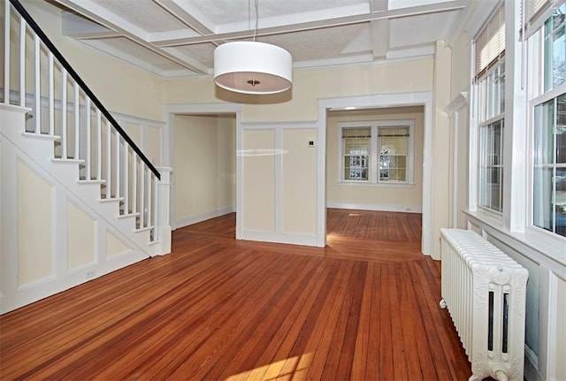 entryway with coffered ceiling, radiator, wood finished floors, stairs, and beam ceiling