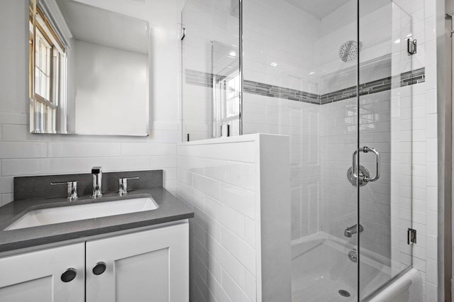 full bath featuring bath / shower combo with glass door, backsplash, tile walls, and vanity