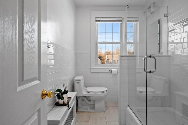 full bathroom with tile patterned flooring, a shower with door, toilet, and tile walls