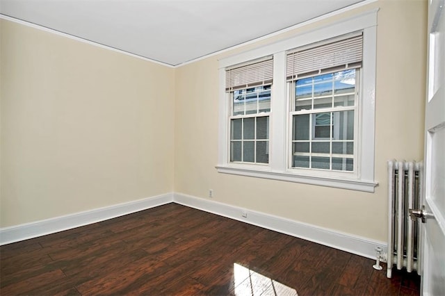 spare room featuring dark wood-style flooring, radiator heating unit, and baseboards