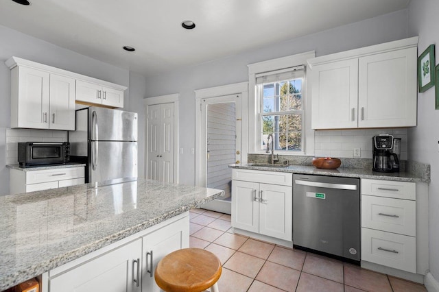 kitchen featuring appliances with stainless steel finishes, backsplash, a sink, and white cabinets