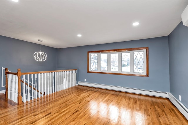 unfurnished room featuring a baseboard heating unit and wood finished floors