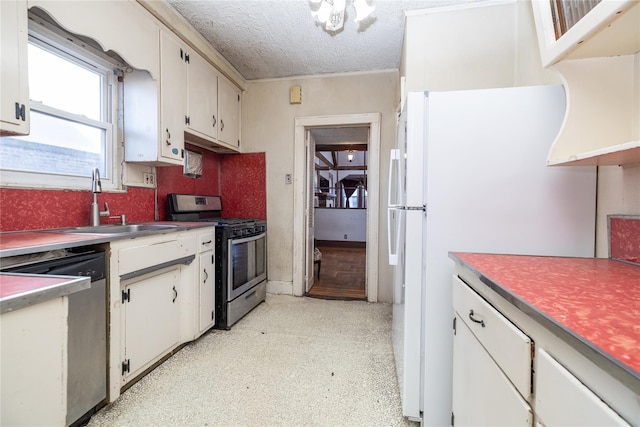 kitchen featuring stainless steel appliances, light countertops, white cabinetry, a sink, and a textured ceiling