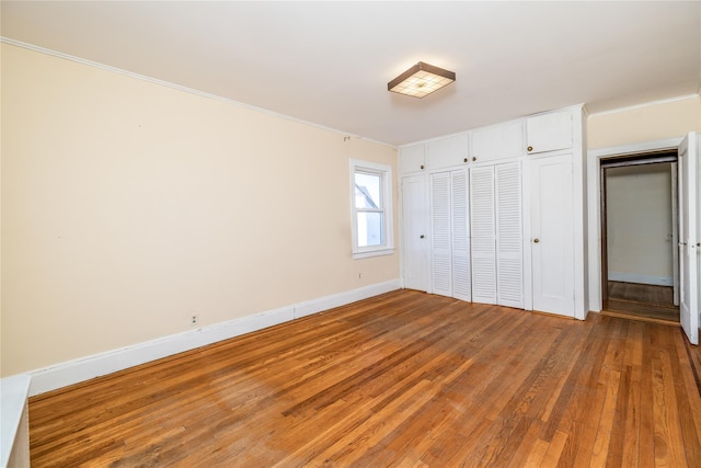 unfurnished bedroom with a closet, wood finished floors, and baseboards