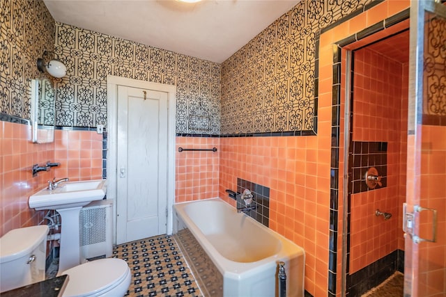 bathroom featuring wainscoting, a garden tub, tile walls, and toilet